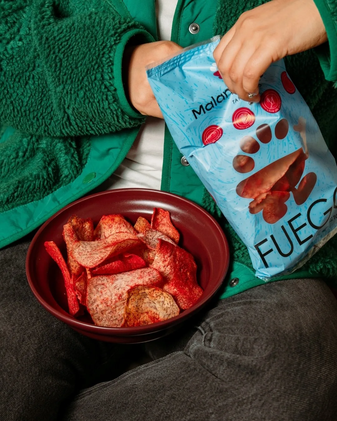 Bowl guinda con chips de malanga junto a una bolsa de Malanguísimas Fuego